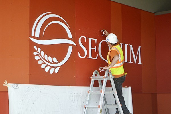 Tony King with United Reprographics of Kent installs the City of Sequim’s logo and name at the entryway of the Sequim Civic Center on April 27.