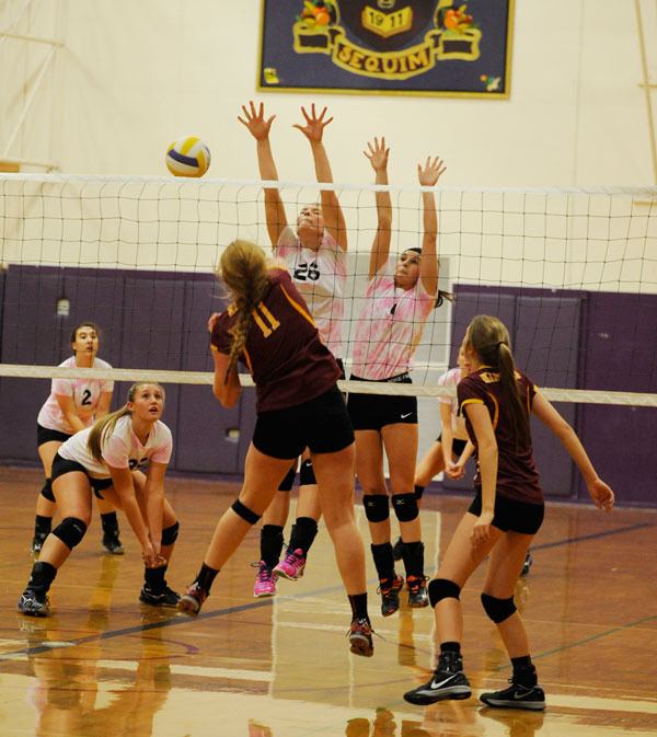 As Sequim’s Lillian Oden (2) and Jayden Overby-Morgison (35) look on