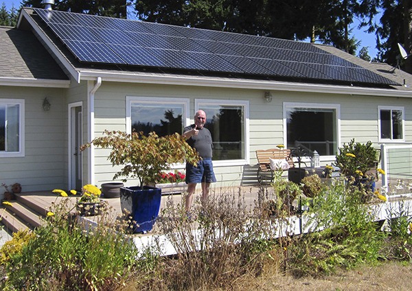 Glenn Robards of Sequim stands in front of his 9.81-kW roof-mounted solar array. This array powers his home and fuels his Tesla S all-electric car.