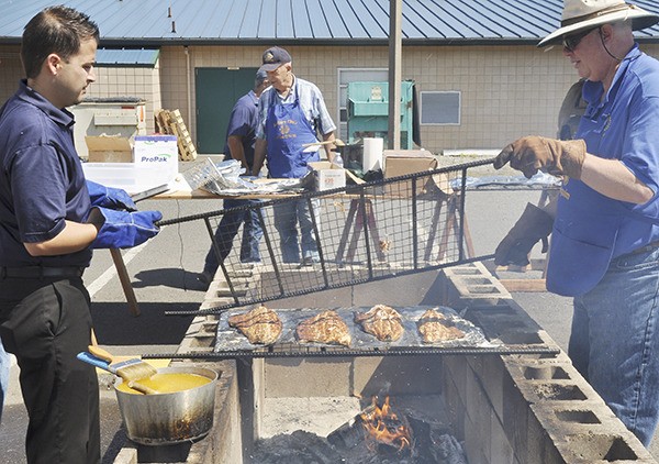 Rotarians tend to a fresh batch of salmon at Sequim Noon Rotary’s 47th annual Salmon Bake & BBQ on Aug. 9 at the Sequim Boys & Girls Club.