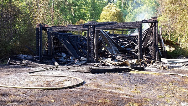 What's left of a workshop in Sequim smolders after a July 15 fire.