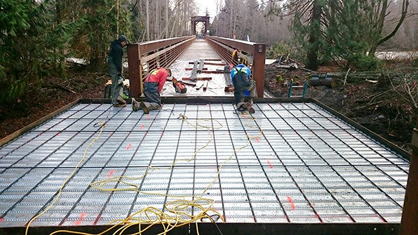 Workers from Nordland Construction of Marrowstone Island attach the deck and lay rebar on the new viewing platform located midway along the new 750-foot bridge that is replacing a trestle damaged by flooding.