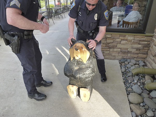 Sequim Police officers look over a carved wooden bear reported missing from the Black Bear Diner since early March.