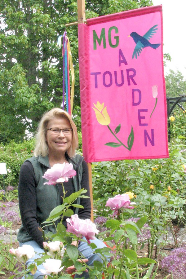 Tour chairman Karen Mahalick poses with a festive flag for the Petals and Pathways Home Garden Tour.