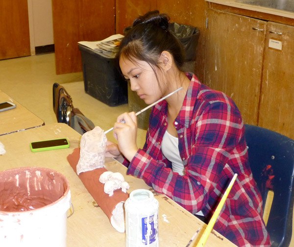 Sequim High School student Shayli Schuman paints her dwarf owl perched on a log. In mid-March she and classmates were creating bird sculptures for BirdQuest. Sequim Gazette photo by Patricia Morrison Coate