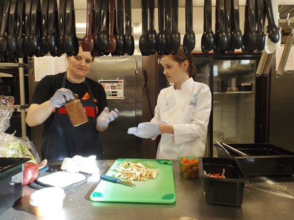 Food service staffer Melody Janssen and Greywolf Elementary School fifth-grader Rea Douglas team up to create Dry-rubbed Mesquite Chicken Salad during the Kids Chopped event on March 19 in the Sequim High School cafeteria’s prep kitchen.