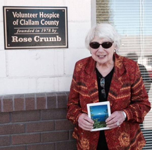 Rose Crumb stands by a sign in her name after being honored at the Volunteer Hospice of Clallam County.