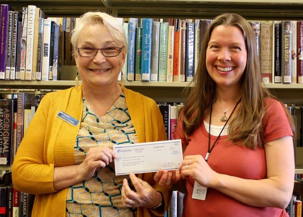 Sequim Columbia Bank manager Kathryn Gates (left) awards a check to Sequim Library manager Emily Sly  a $500 donation for the newly formed North Olympic Library Foundation.