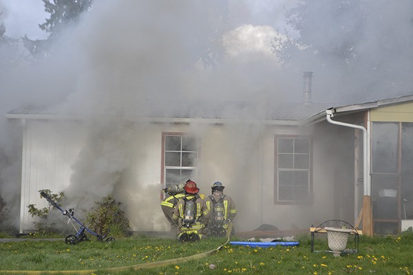 Fire crews with Clallam County Fire District 3 vent smoke and use hoses to try to extinguish a fire on Monday evening in Carlsborg.