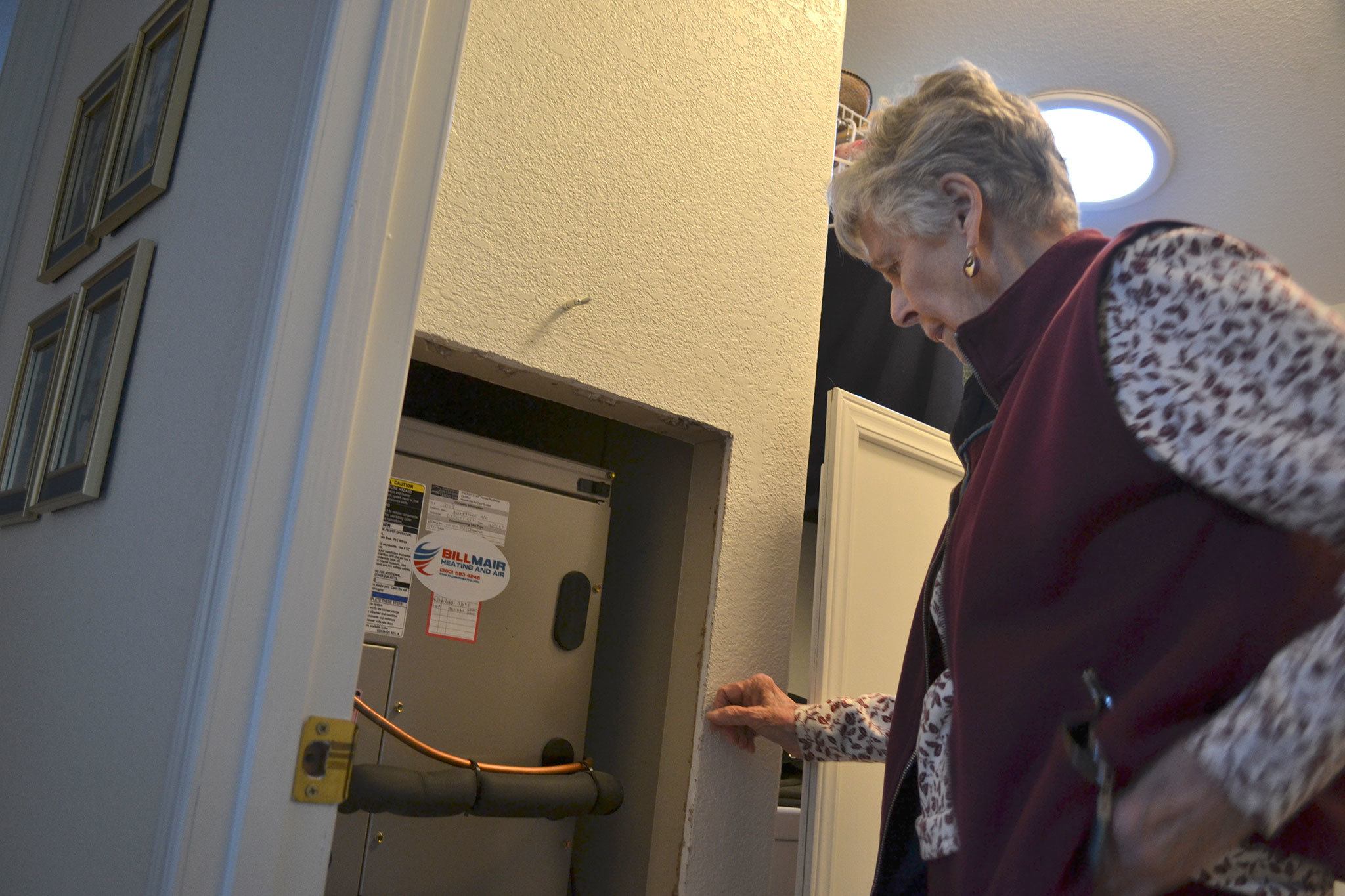 Carolyn Crane of Sequim stands by her furnace where a scammer attempted to charge her $1,500 to remove a dirt clod he likely placed inside. Crane and others report of several recent attempts to scam people for false heating services. Sequim Gazette photo by Matthew Nash