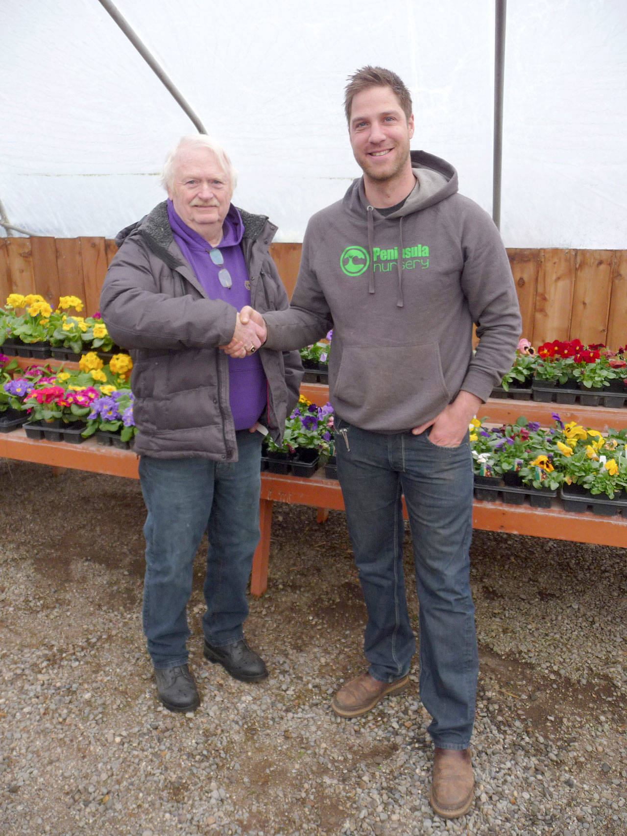 Roger Fell, a longtime nurseryman and owner of Peninsula Nurseries, shakes hands with George Peterson, who has purchased the business and the property. Sequim Gazette photo by Patricia Morrison Coate