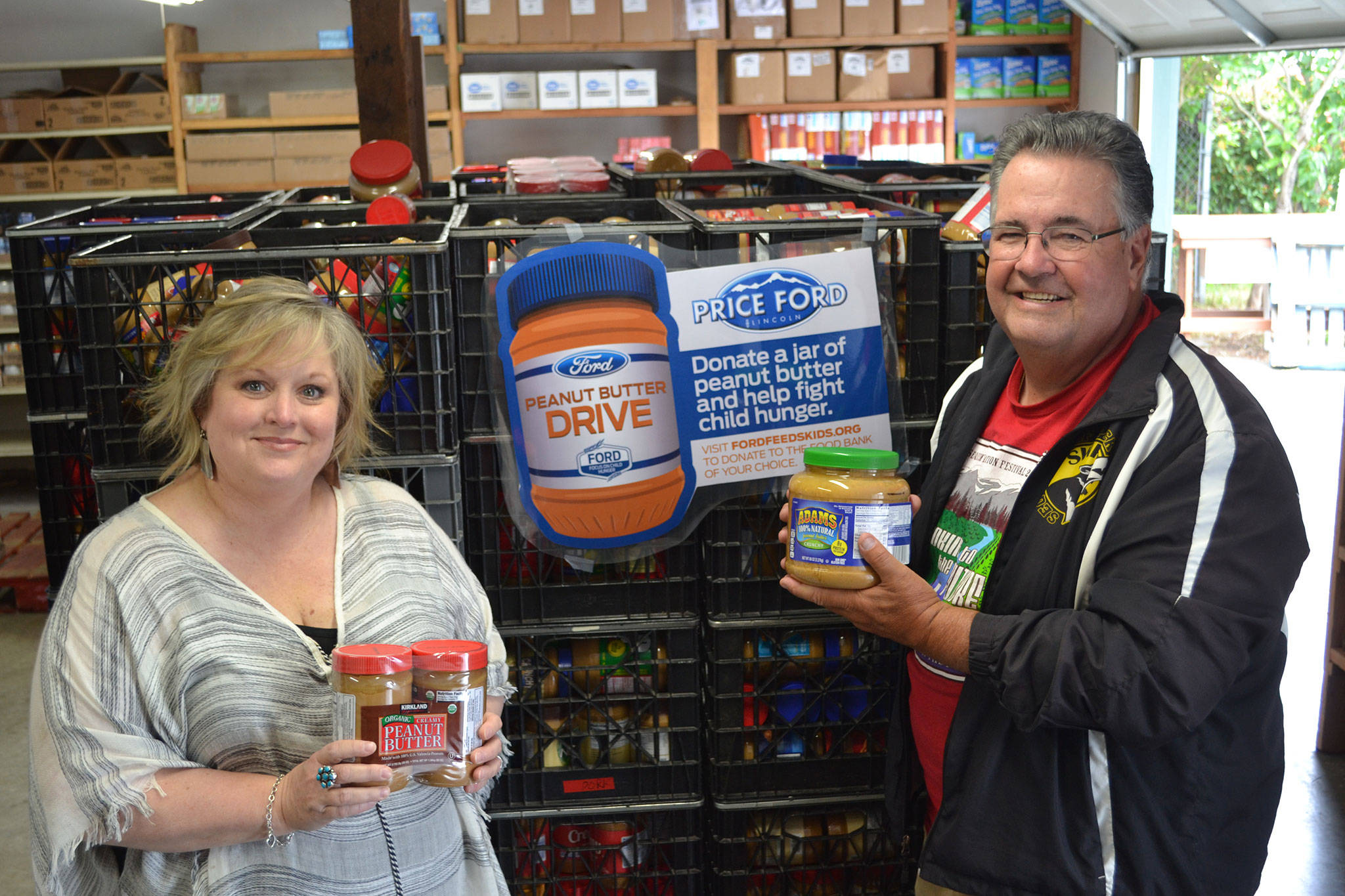 Andra Smith, executive director of the Sequim Food Bank, and Stephen Rosales, board president for the food bank, stand with more than 3,000 jars of peanut butter in the Sequim Food Bank. The peanut butter was donated during the Price Ford Peanut Butter Drive last weekend at local grocery stores. With cash donations, they estimate they’ll bring in just over 4,000 jars to help local youth. Sequim Gazette photo by Matthew Nash