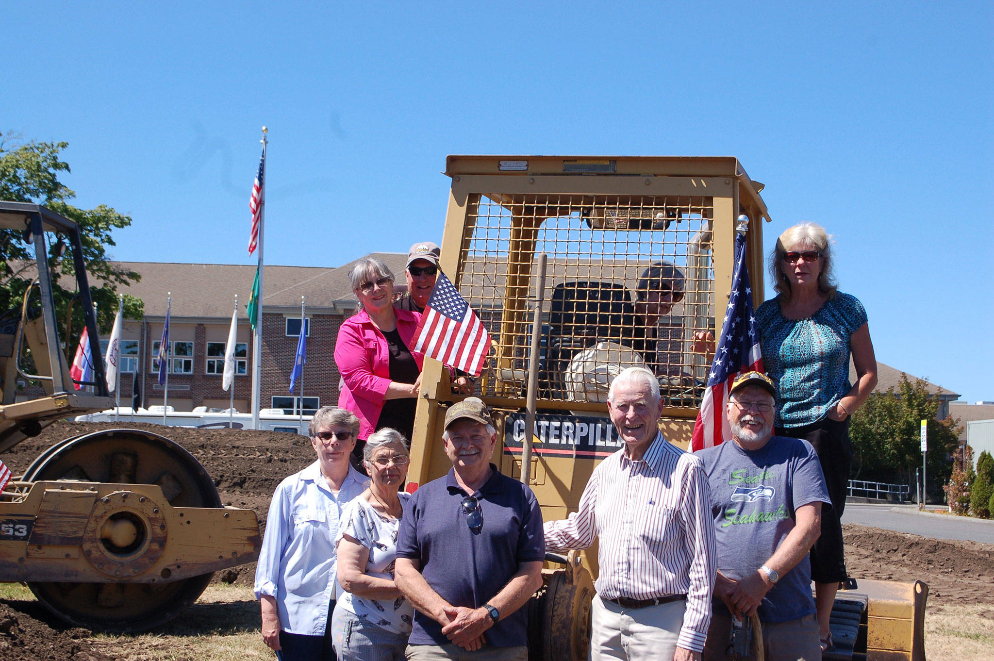 Sequim Museum & Arts Board of Trustees from bottom left, Nancy Goldstien, Bev Majors, Bob Stipe, Bob Clark and Bud Knapp; top left, Judy Reandeau Stipe, Greg Fisher, Hazel Ault (inside cab) and Trish Bekkevar stand where John Dickinson, owner of We Dig It Excavation, is preparing the ground for construction of Sequim Museum & Arts’ new exhibit building on North Sequim Avenue. Sequim Gazette photo by Erin Hawkins