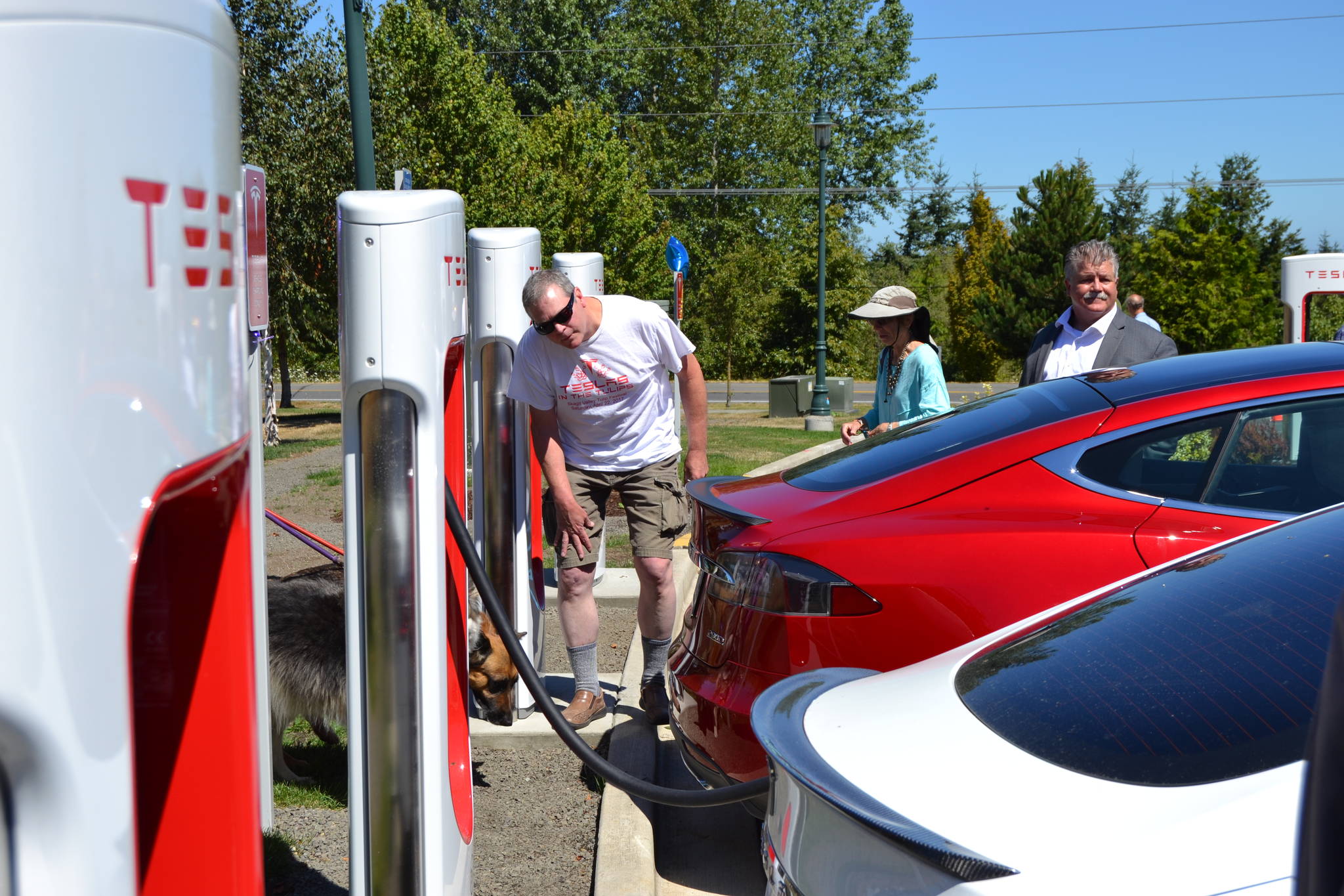 Brick Ayola of Port Angeles looks at two Tesla cars at the ribbon cutting for the new Supercharger station at the Sequim Holiday Inn Express & Suites. Ayola said he’s owned his Tesla for close to five years and drove to the area from Chicago. He’s looking forward to a Supercharger station opening in Forks so that he can make the loop around the Olympic Peninsula. Sequim Gazette photo by Matthew Nash