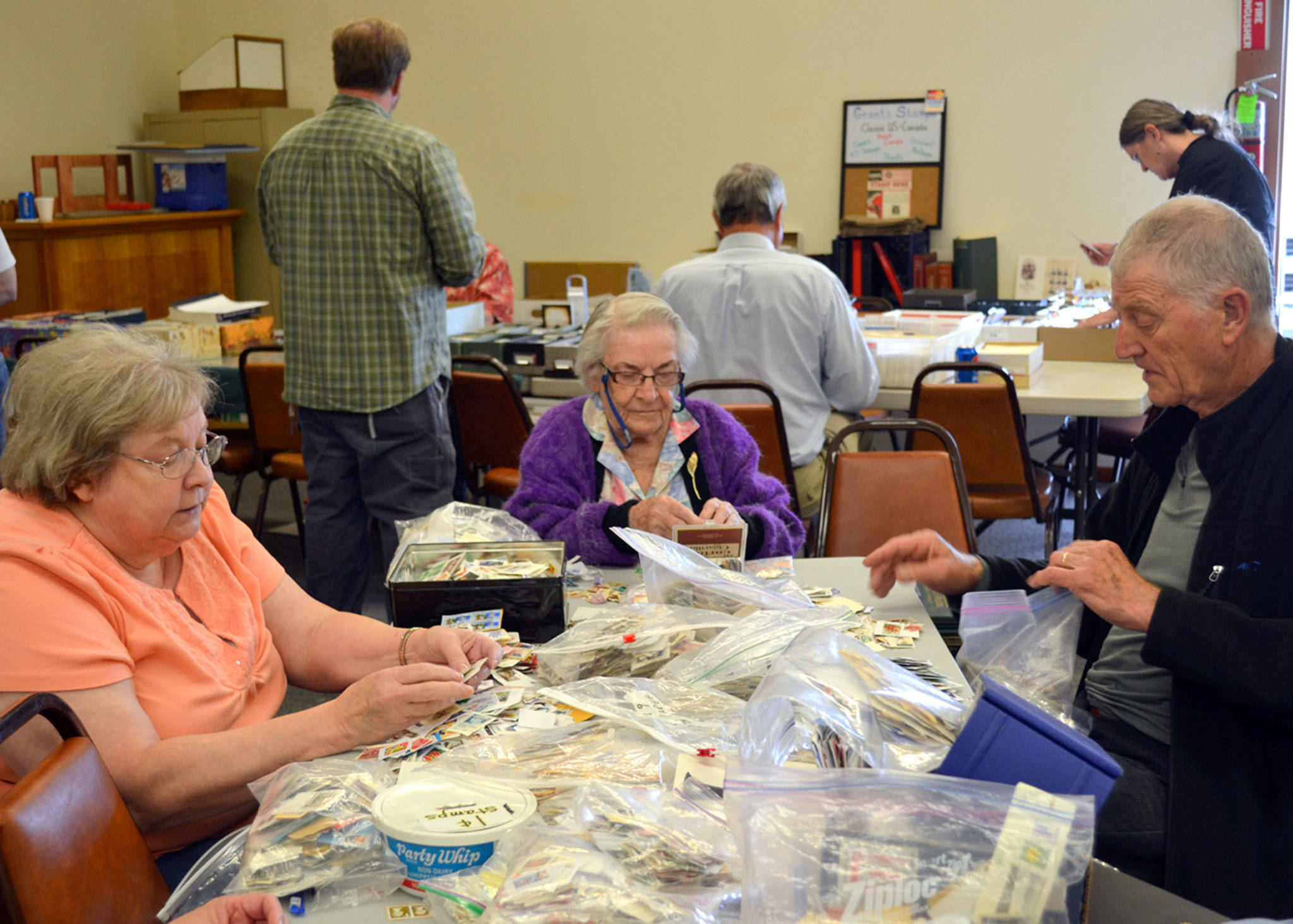 Stamp collectors, from left, Jan Schultz of Port Angeles, June Mennell of Sequim and John Plantinga of Victoria, B.C., search for stamps in the penny pile at the Strait Stamp Show in 2015 in the Sequim Masonic Lodge. This year’s 24th annual show runs on Aug. 12 with 15-plus vendors and plenty of stamps to go-around. Sequim Gazette file photo by Matthew Nash