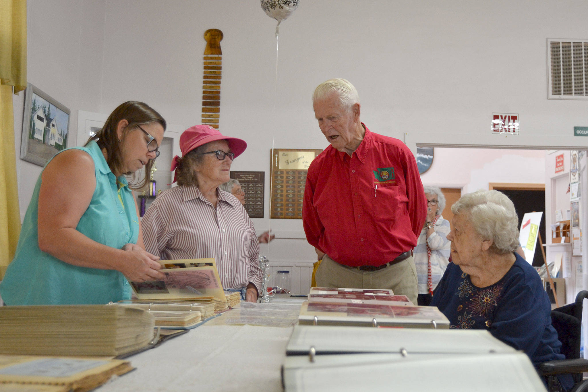 At the 75th anniversary for the Sequim Prairie Grange, from left, Sherry Ritchie, Joan Ritchie, Bob Clark, grange master, and Beanie Ellis look through the grange’s scrapbooks and talk about old times on Aug. 9. Sequim Gazette photo by Matthew Nash