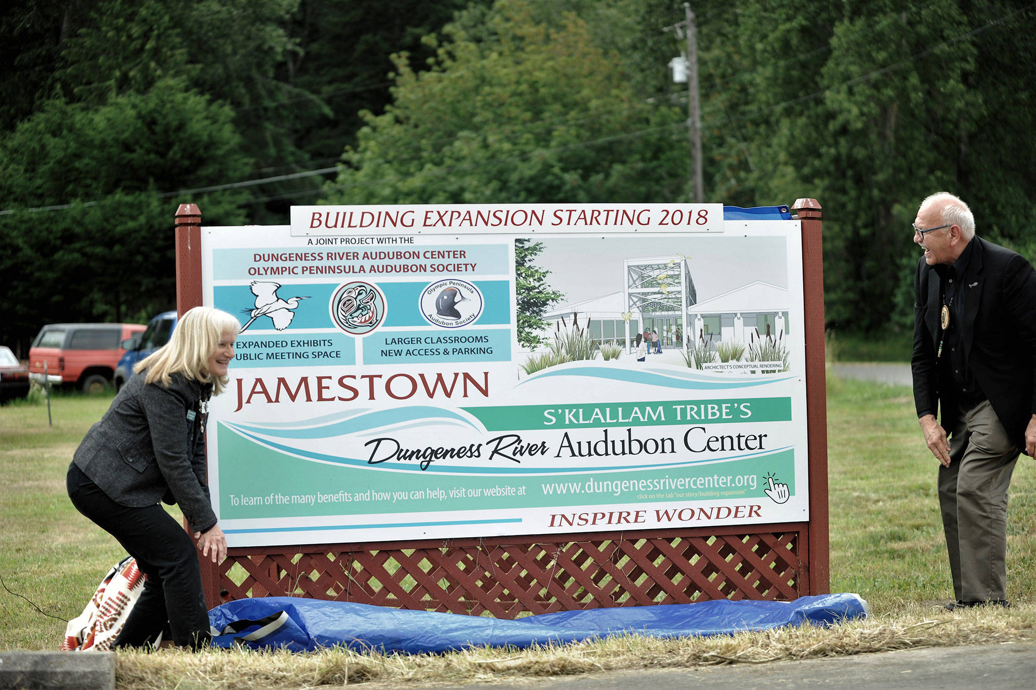 Annette Hanson, capital campaign committee chair for the expansion of the Dungeness River Audubon Center, and Ron Allen, tribal chairman for the Jamestown S’Klallam Tribe, reveal a new sign on June 22 at the entrance to the Railroad Bridge Park announcing the campaign to build a new parking lot and expand the center. Sequim Gazette photo by Matthew Nash