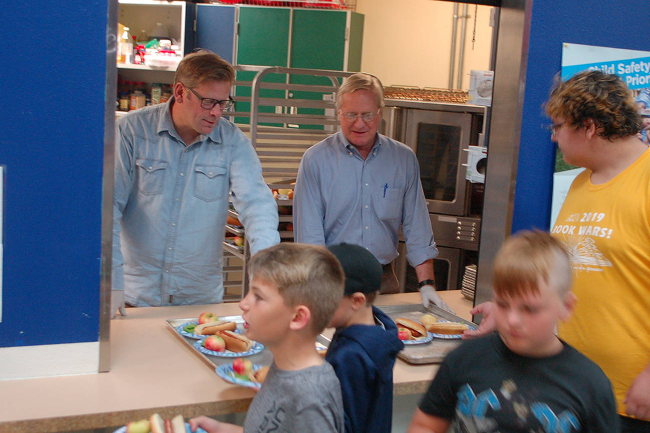 Washington State Reps. Mike Chapman, left, and Steve Tharinger, center, of the 24th legislative district serve lunch for the kids at the Boys & Girls Club in Sequim on Aug. 27. The club serves a free lunch to attendees and to families at several community locations every day during the summer. Sequim Gazette photos by Conor Dowley