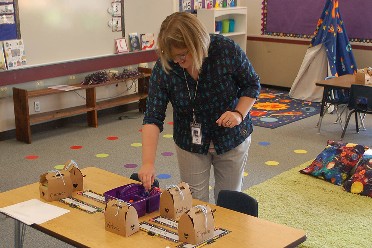 Greywolf Elementary School first grade teacher Kylie Douglas laughs as she puts together supplies on one of her students’ tables. Douglas is a new teacher at Greywolf, having taught in Tennessee before moving to the area in 2018, but will miss the first two weeks of the school year after undergoing back surgery on Sept. 4. “This just reinforces for me that our substitutes are the real heroes of the school district,” she said. Sequim Gazette photo by Conor Dowley