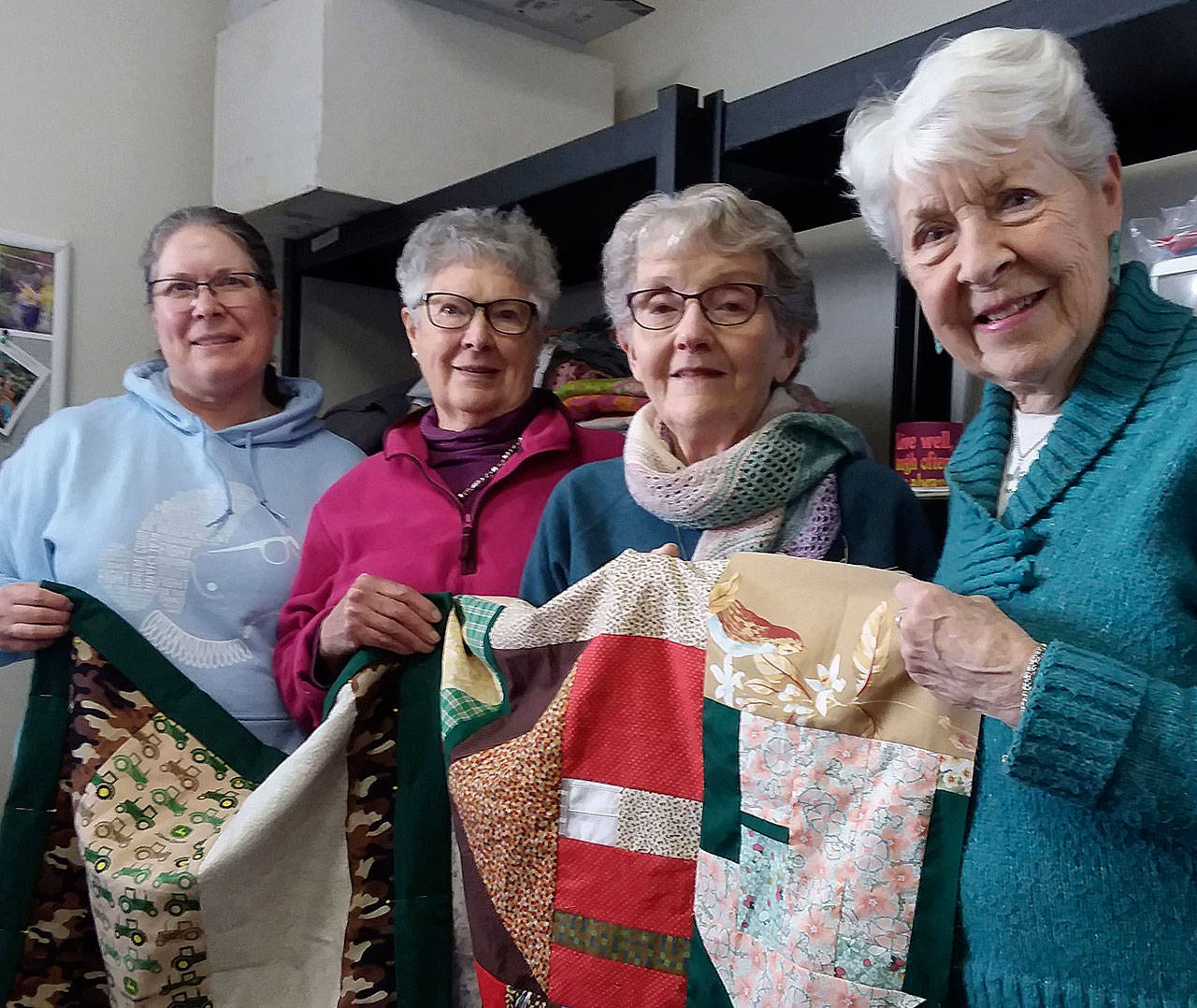 Showing a completed child’s quilt and an unfinished quilt top are, from left Alane Olson, Jane Olson, Ruthie Armstrong and Jean Cameron, four of the women who have made more than 5,000 quilts at Dungeness Valley Lutheran Church in the past quarter-century. Submitted photo