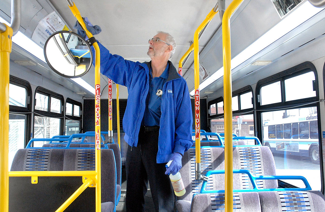 Clallam Transit driver Pete Sekac wipes down surfaces on a transit bus between runs on March 26 at The Gateway transit center in Port Angeles. The transit service has suspended fares due to the COVID-19 emergency and asking riders to enter from the back door of the bus whenever possible, and then to practice social distancing while aboard. Photo by Keith Thorpe/Olympic Peninsula News Group