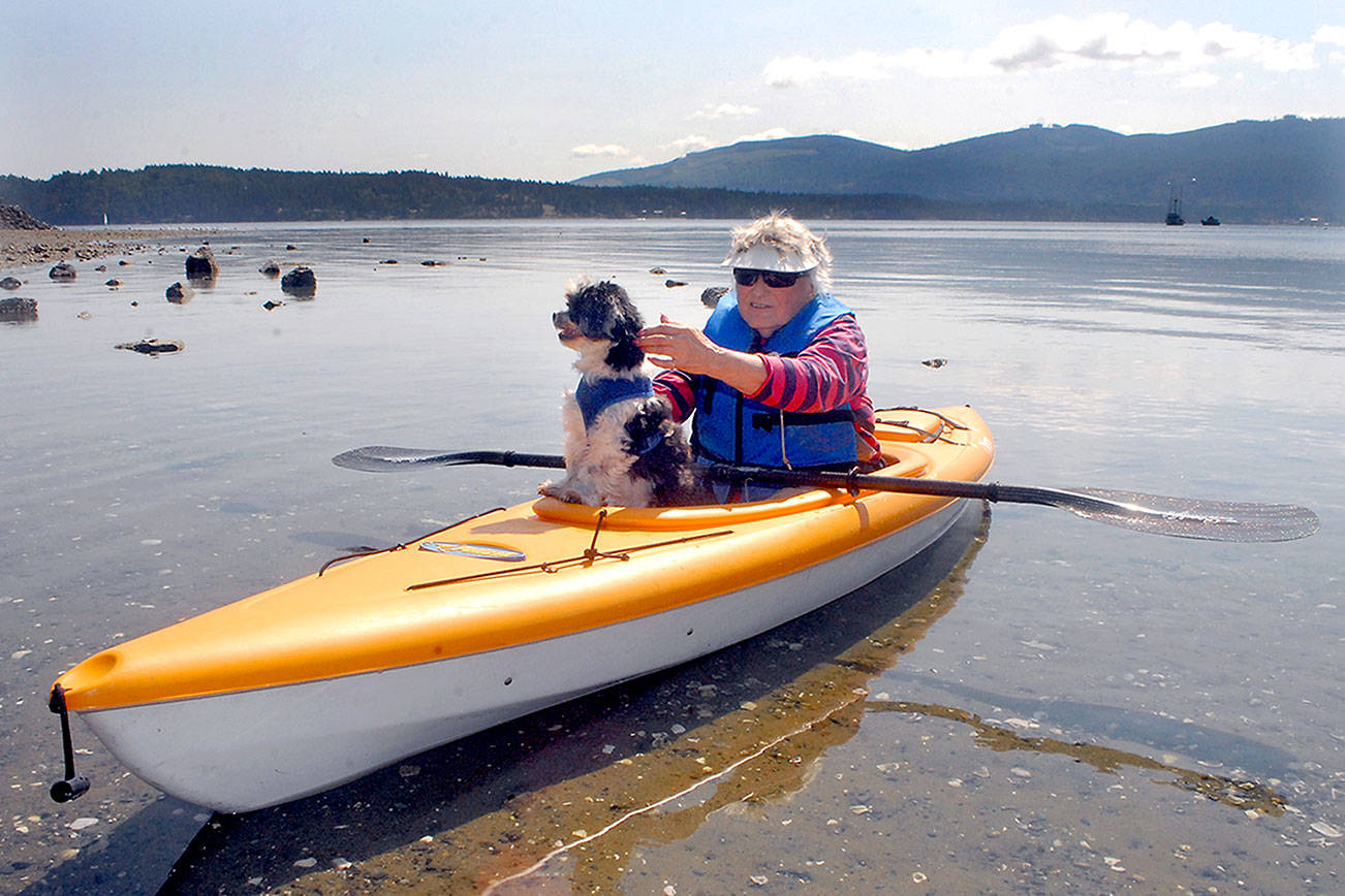 Judy Larimore of Sequim assists her dog, Tucker, after a paddle on Sequim Bay near John Wayne Marina near Sequim. Larimore said the pup often accompanies her on kayak adventures. Photo by Keith Thorpe/Olympic Peninsula News Group