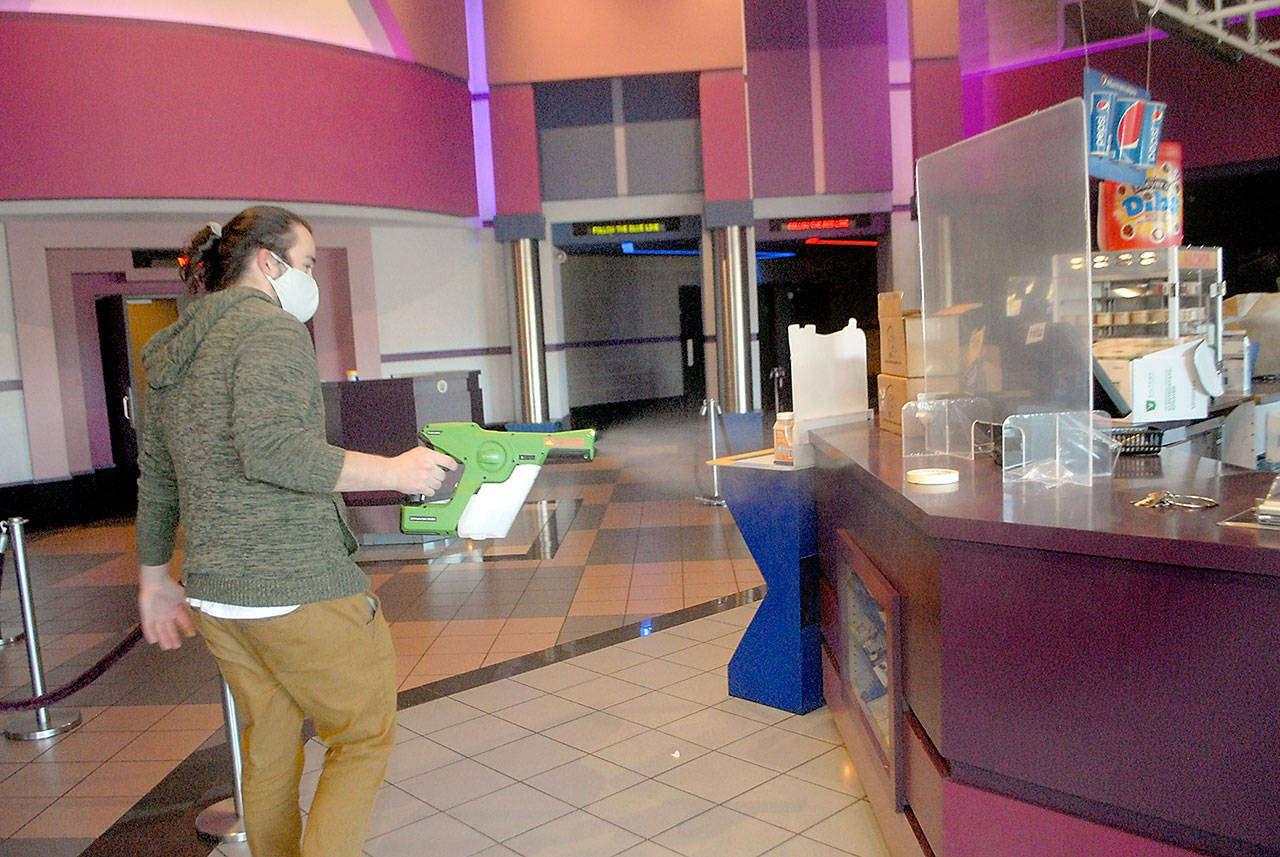 Deer Park Cinema manager Casey Chapman sprays disinfectant mist around the concession stand of the Port Angeles theater complex lobby Thursday, Oct. 22, in preparation for reopening Oct. 30. (Photo by Keith Thorpe/Olympic Peninsula News Group