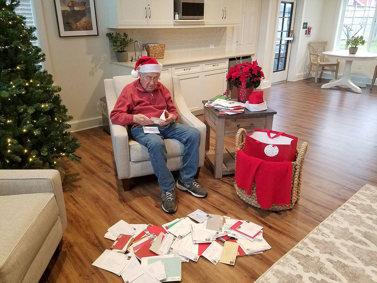 Rodney Hofman opens one of hundreds of Christmas cards sent to him and fellow Dungeness Courte Memory Care residents, following a request from Hofman’s family members on social media. Photo courtesy of Dungeness Courte Memory Care