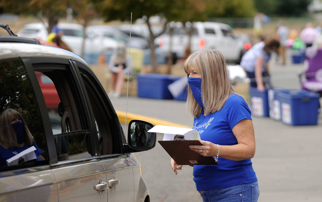 Third-grade teacher Sheri Burke hands out packets of school curriculum and materials at Greywolf Elementary School on Sept. 2, the first day of school for Sequim students. Elementary school level Sequim students are headed back to classes for in-person instruction on Jan. 26 after a two-month remote learning hiatus. Sequim Gazette file photo by Michael Dashiell