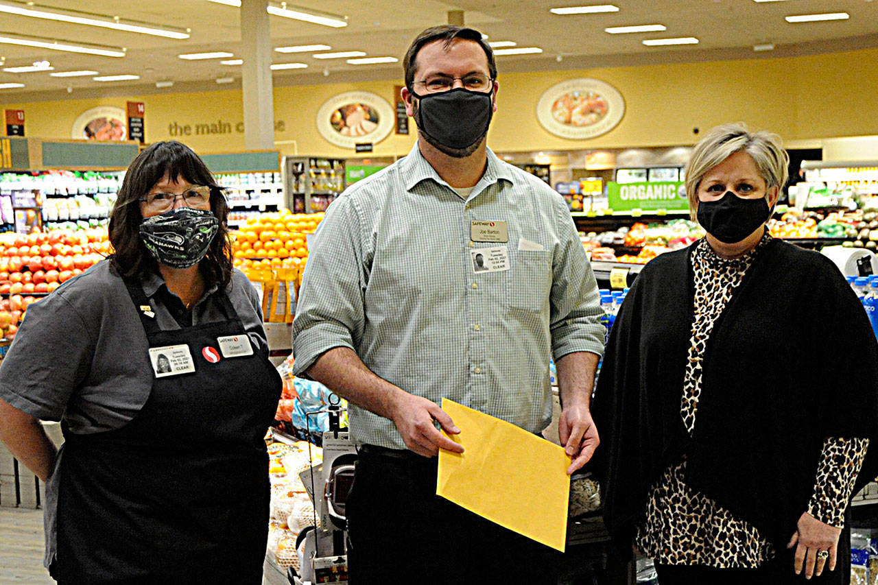 Sequim Safeway checker Colleen Tenneson and manager Joe Barton helped raised more than $87,000 from customer donations for the Sequim Food Bank fundraiser over November and December. Andra Smith, food bank executive director, on right, said donations will go towards gift cards, which she loves because “it allows families to choose and make their own nutritional decisions.” Sequim Gazette photo by Matthew Nash