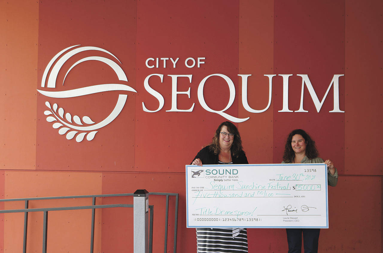 At left, Shelli Robb-Kahler, Sound Community Bank vice president and hub branch manager, presents a check for $5,000 to Sequim Interim City Manager Charisse Deschenes for sponsorship of the 2022 Sequim Sunshine Festival drone show. Photo courtesy of City of Sequim