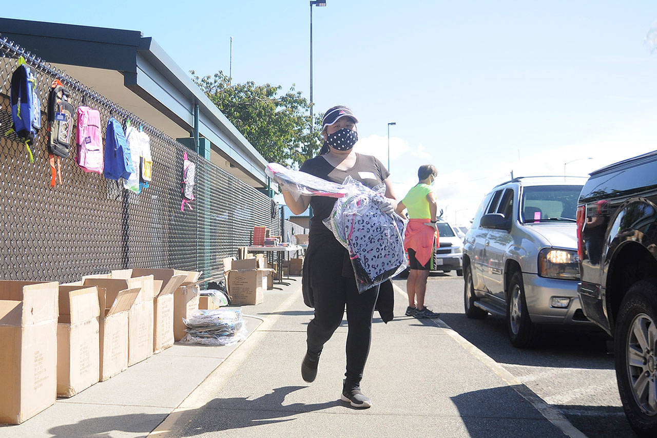 May Smith helps hand out backpacks, joining dozens of other volunteers at the annual Back to School Fair, held at Helen Haller Elementary School and the Sequim Boys & Girls Club in August 2020. Normally held indoors at the club, the fair was shifted to a “drive through” style event due to COVID-19 health restrictions and concerns. This year’s event is slated for Saturday, Aug. 28. Sequim Gazette file photo by Michael Dashiell