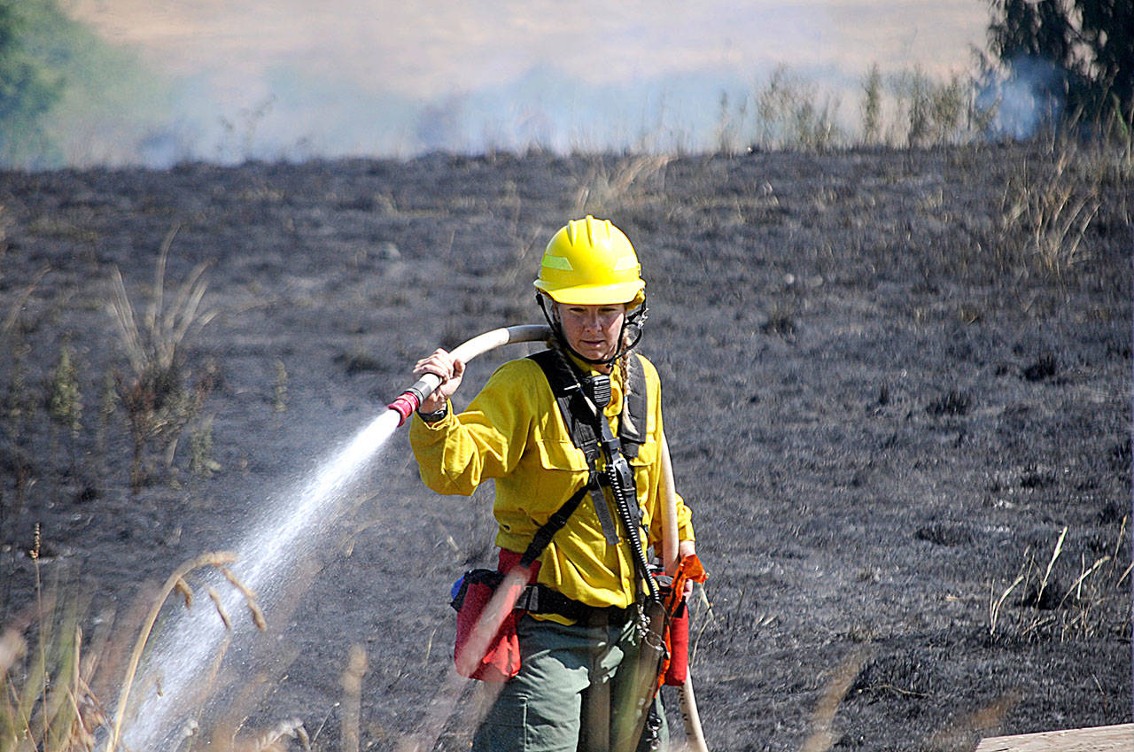 Firefighter/paramedic Margie Brueckner with Clallam County Fire District 2 looks for hot spots at a brush fire near Sherburne Road on July 27. Sequim Gazette photos by Matthew Nash