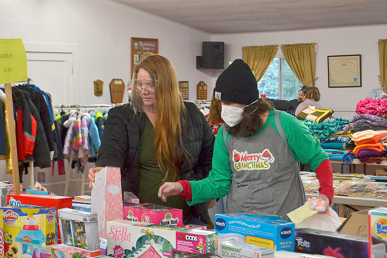 Volunteer Kirsti Turella helps mom Desirae Cortez look for just the right toy for her children in 2020 at Toys for Sequim Kids. The Sequim Community Aid sponsored event takes place Dec. 15 at Sequim Prairie Grange. Sequim Gazette file photo by Matthew Nash