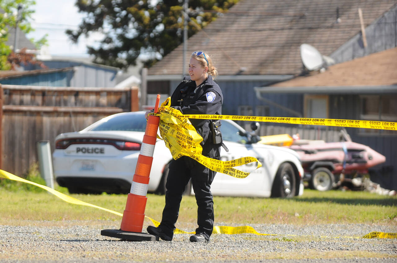 A Port Angeles police officer cordons off an empty lot at West Washington Street and Third Avenue Thursday morning as law enforcement officials investigate an incident in the area. Sequim Gazette photo by Michael Dashiell