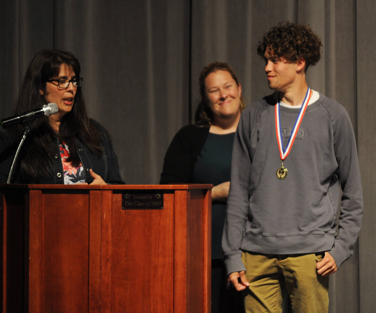 Anita Benitez, world languages teacher at Sequim High School (left), congratulates SHS senior Adrian Brown for his work to pass the seal of Biliteracy exam at the SHS scholarship awards ceremony on June 1; SHS assistant principal Erin Fox looks on. Sequim Gazette photo by Michael Dashiell