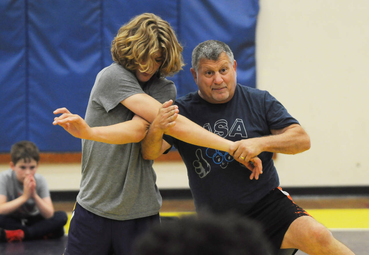 Former collegiate, national and world wrestling champion Gene Mills, right, demonstrates a move with Sumner’s Cody Miller at a summer camp in Sequim last week.