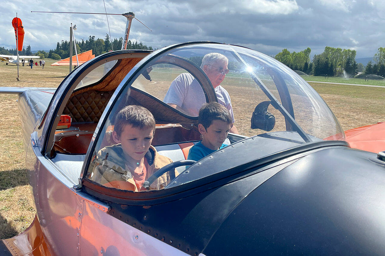 Sequim Gazette photos by Matthew Nash
Kevin Tracy of Sequim helps brothers Silas, 7, and Zeke, 9, Smith sit in his 1946 Ercoupe 415-C airplane at the Air Affaire at the Sequim Valley Airport on Aug. 27.