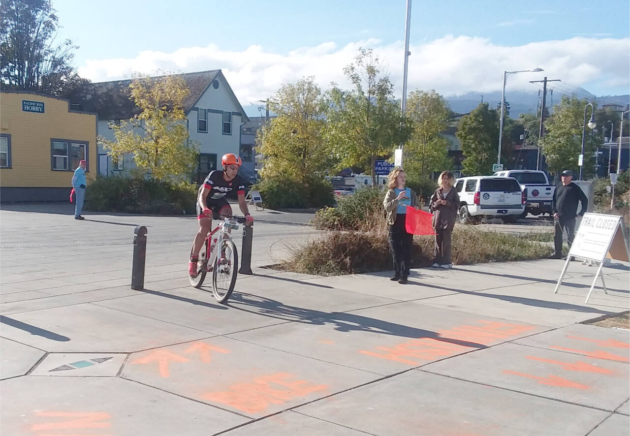 Photo by Pierre LaBossiee/Olympic Peninsula News group / Ian Mackie pulls into the exchange zone on the Port Angeles waterfront after completing the mountain biking leg at the Sept. 24 Big Hurt.