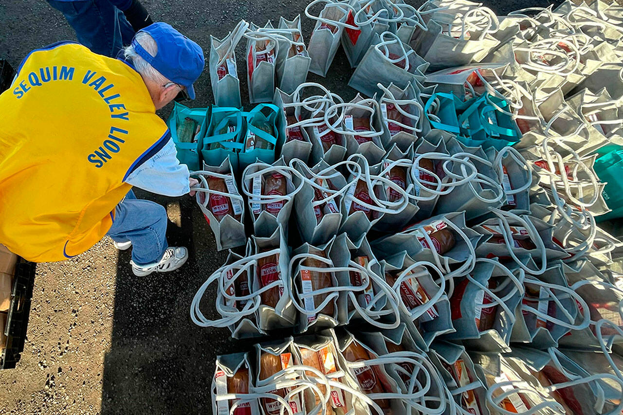 Sequim Gazette photo by Matthew Nash/ Pat Phillips, past zone chairman with the Sequim Valley Lions, grabs some meal bags to place in a trunk on Nov. 18 during the Family Holiday Food Bag Distribution event. The event resumes on Dec. 16 in Carrie Blake Community Park.