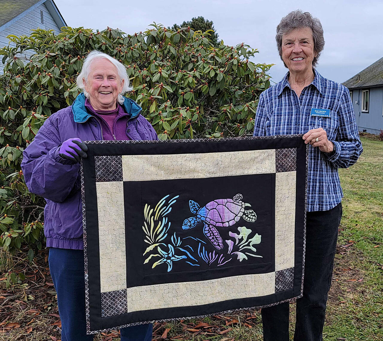 Photo by Carmi Standish/Sequim Bay Yacht Club 
Pam Cameron, left, receives “The Spirit of Honu” from Sue Baden in the raffle held by Sequim Bay Yacht Club.