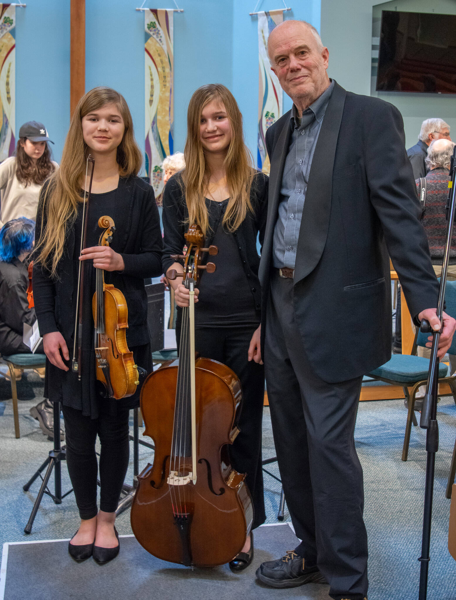 Sequim Gazette photo by Emily Matthiessen
“Guest musicians” Eliana and Claire Montgomery of Quilcene join Sequim Community Orchestra conductor Phil Morgan-Ellis at a Feb. 11 concert in Sequim. See more photos from the concert at sequimgazette.com.