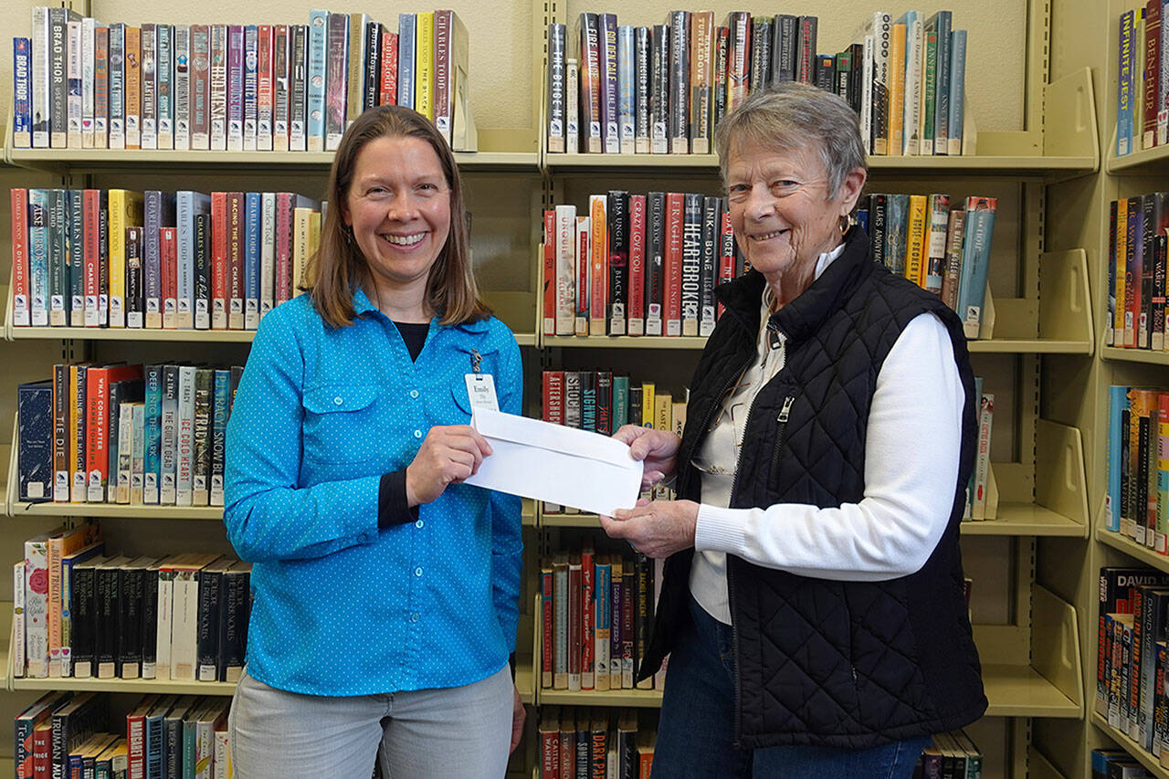 Photo courtesy of NOLS/ Liz Phelps, former president of Friends of Sequim Library, right, presents a check to Emily Sly, branch manager of Sequim Library, in 2022. Phelps, who died in May, has helped lead monthly book sales for years and raised hundreds-of-thousands of dollars for the library.