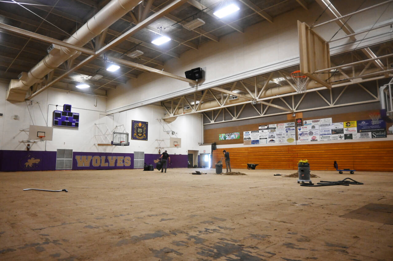 Sequim Gazette photo by Michael Dashiell / Work crews clear debris from the Sequim High School gymnasium floor last week. The decades-old floor used for volleyball and basketball games and gym classes is getting a makeover, funded by a capital projects levy voters approved in February 2021.