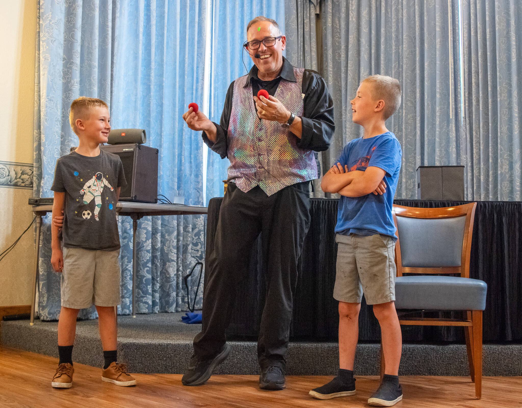 Sequim Gazette Photo by Emily Matthiessen / Aldan (left) and Jonah Huegel, brothers, assist “The Magic of Rich” in some tricks at the Fifth Avenue senior independent living community on Aug. 19.