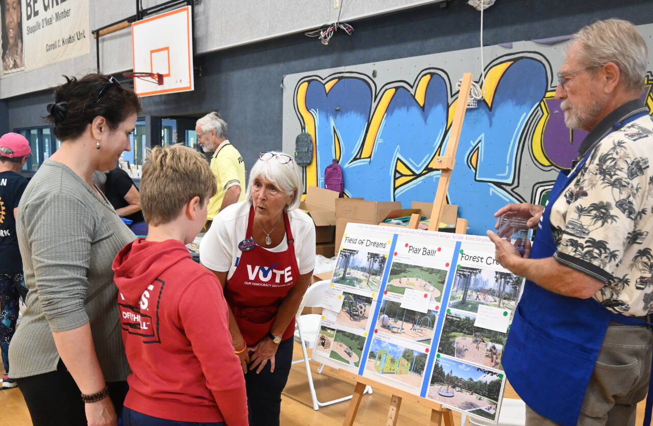 Sequim Gazette photo by Michael Dashiell / Stephanie and Jim Sherman with the League of Women Voters talk with Elijah Malkasian, 9, of Sequim, at the Aug. 26 Back to School Fair, about playground options the City of Sequim is considering. Fair attendees were asked to vote on their favorite of three choices; more than two-thirds of the respondents picked “Forest Creature,” league representatives said.