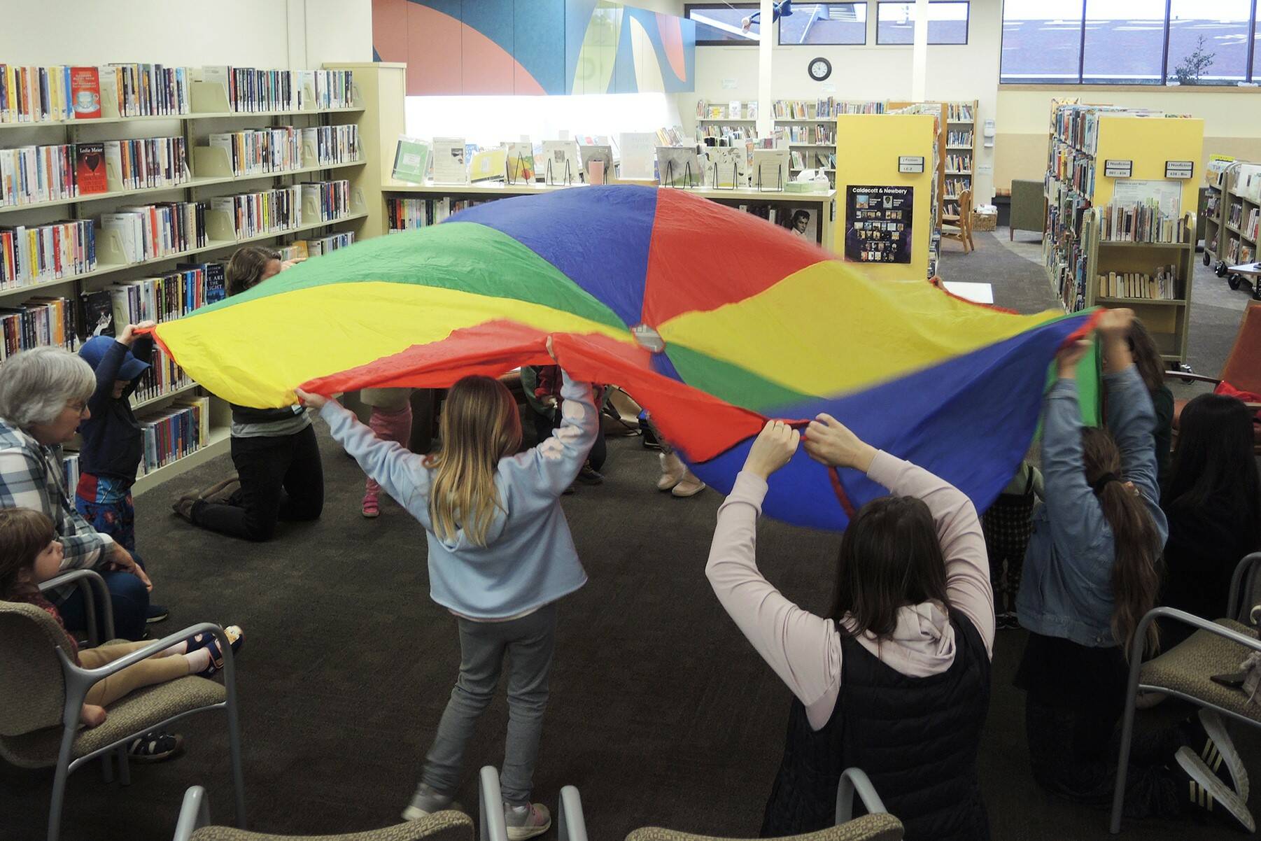 Photo courtesy of North Olympic Library System / Families play with a brightly colored parachute on Jan. 2 at Storytime in the Sequim Library.