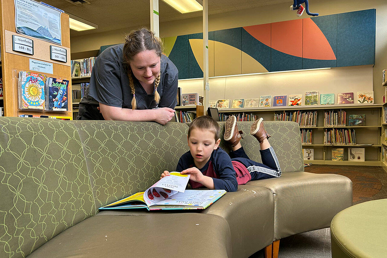 Sequim Gazette photo by Matthew Nash
Rachel Tax talks to her four-year-old son AJ while he reads a book in the children’s section of the Sequim Library on March 9. She said they visited one last time before it closes temporarily for construction so that her daughter Anna-Marie could check out some cat books for a 4-H report.