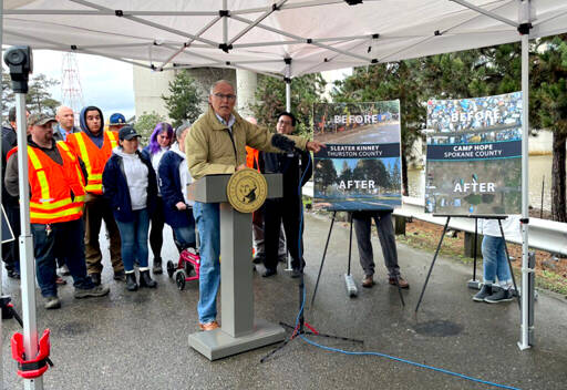 Photo by Laurel Demkovich/Washington State Standard / Gov. Jay Inslee points to the work his homeless encampment initiative has done to clear encampments and transition people into housing. Inslee released his budget proposals surrounding housing and homelessness programs at the site of a former encampment in Seattle.