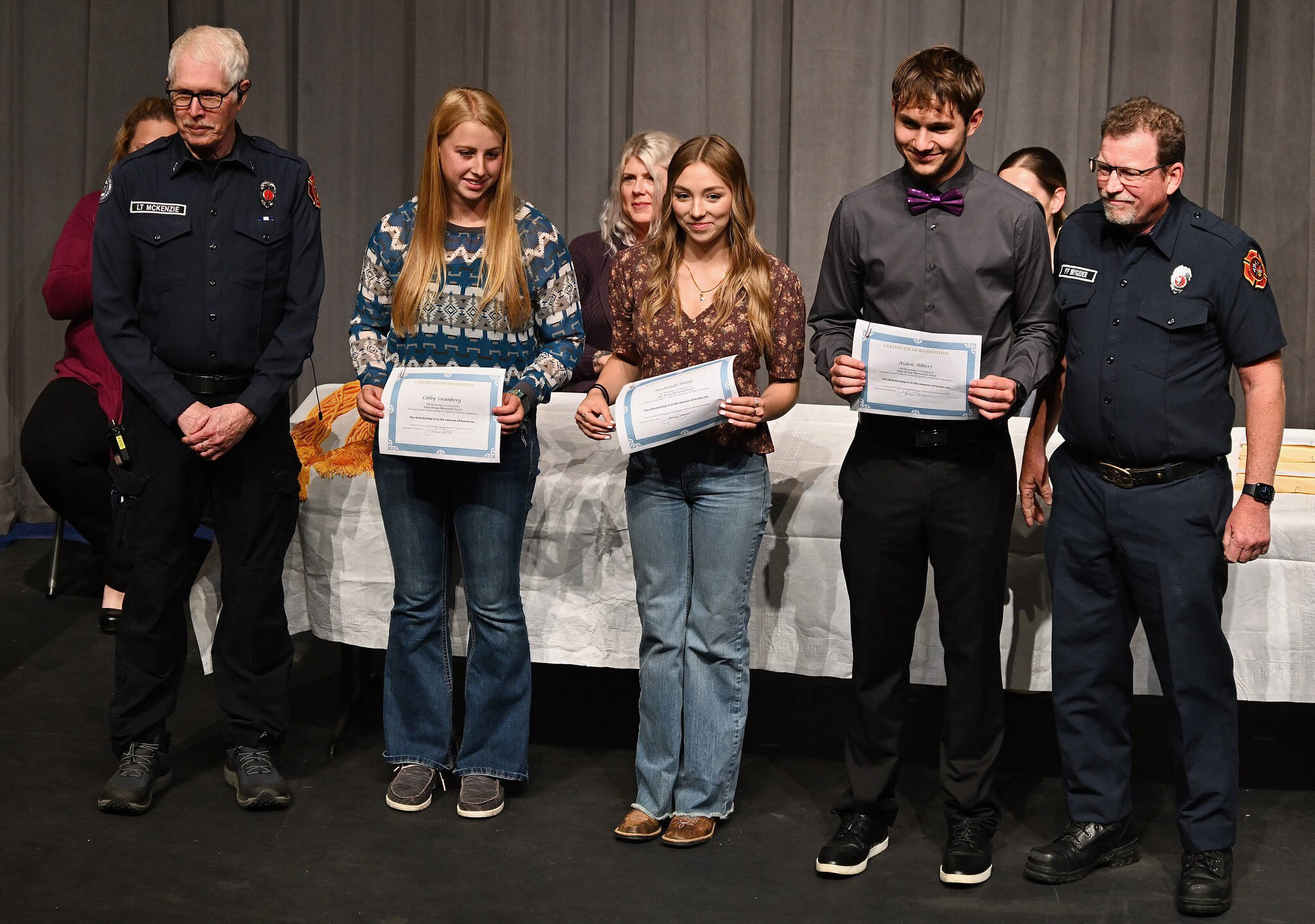 Photos by Jay Cline
At Sequim High School’s Scholarship Night on June 5, Sequim High seniors (from left) Libby Swanberg, Susannah Sharp and Aiden Albers receive Dale Kruse Memorial Scholarship funds from John McKenzie (far left) and John Brygider from Clallam County Fire District 3.
